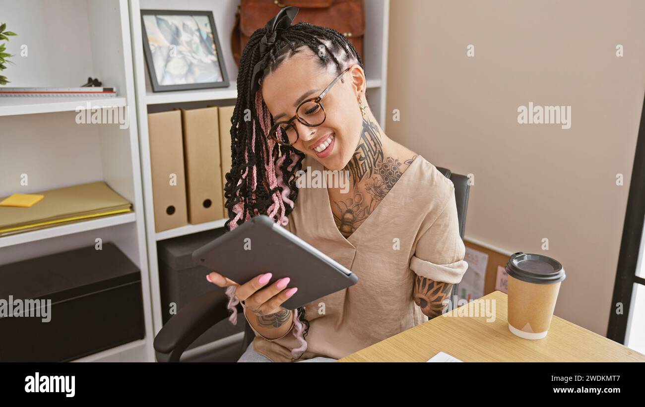 Confident hispanic woman, a smiling arm amputee, masterfully working on touchpad in elegant business office Stock Photo