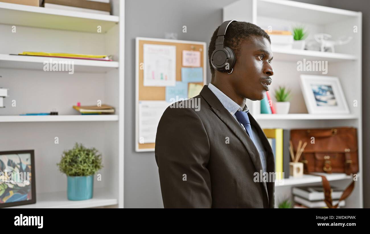 African american man wearing headset in modern office setting listening attentively during a workday. Stock Photo