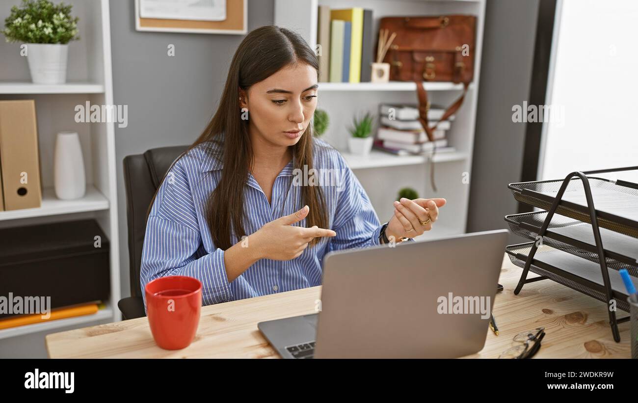 Young hispanic woman having a video call in a modern office setting ...
