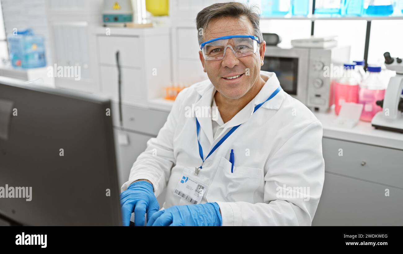 A smiling middleaged man wearing lab coat and safety glasses working