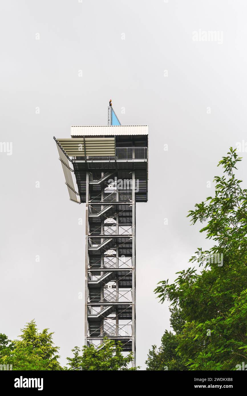 Meuro-Stolln tower in Schipkau, Germany. Metal structure with visible staircase, flagpole, and flag, set against an overcast sky. Stock Photo