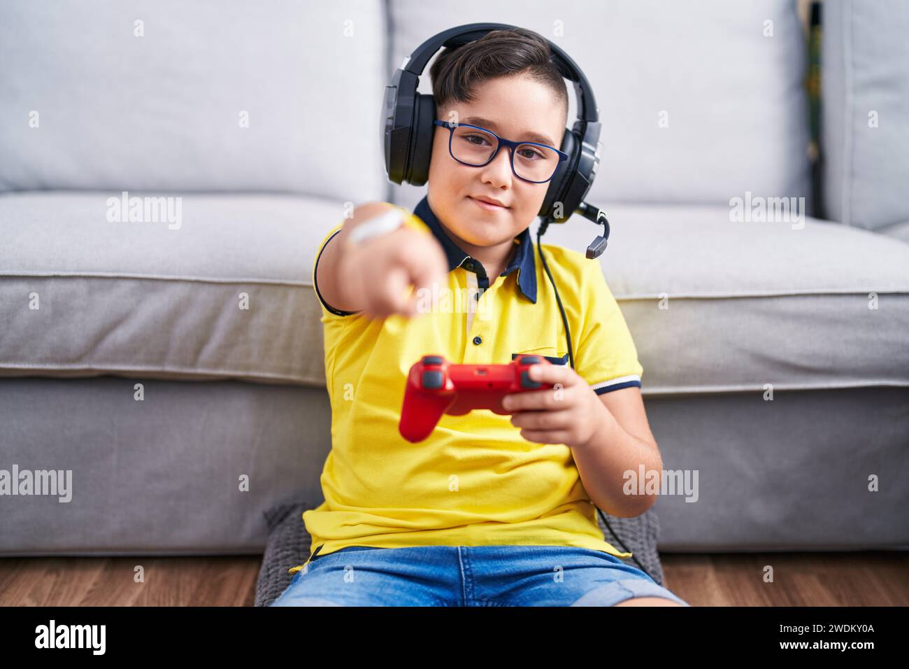 Kid Using Controller Young hispanic kid playing video game holding controller wearing ...