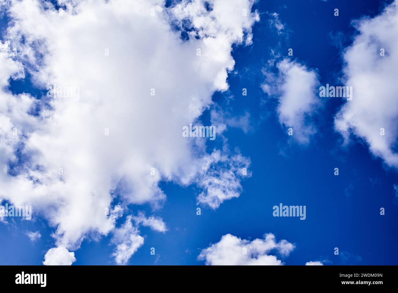 Fluffy white clouds scattered across a vibrant blue sky convey a sense ...