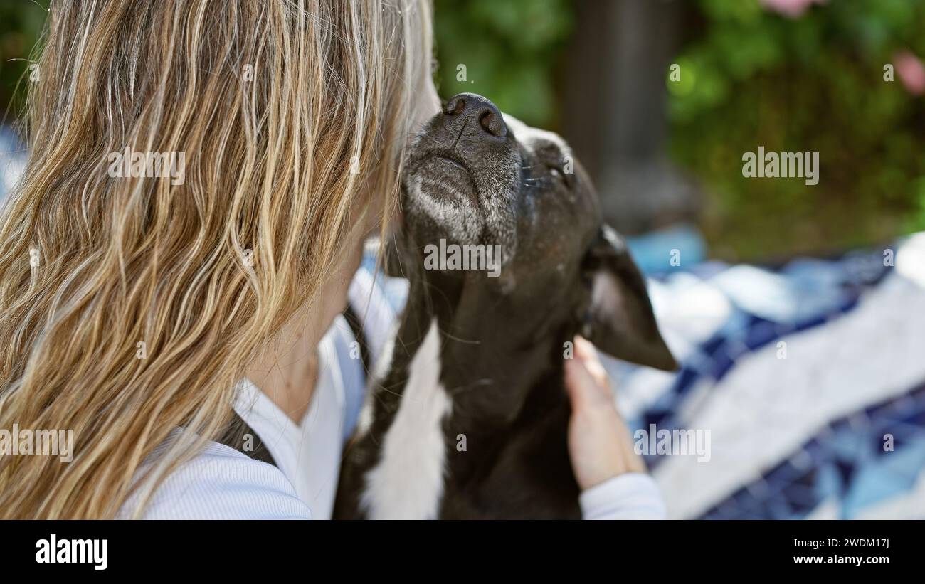 A young woman affectionately pets her black labrador in a serene ...