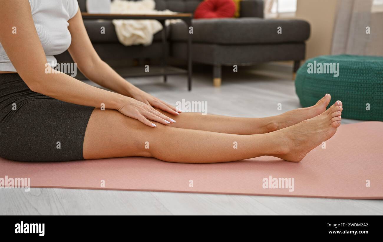 Young blonde woman sitting on yoga mat stretching legs at home Stock ...