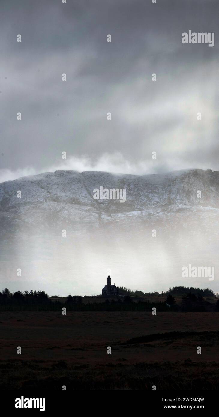 Rain and clouds over a silouetted church in a mountainous landscape in winter Stock Photo