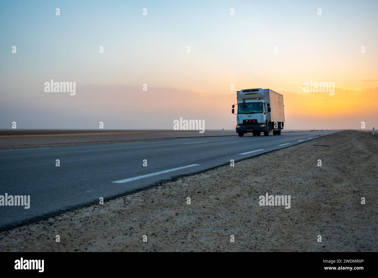 07.11.23 Sahara Desert, Tunisia: Beautiful colourful sunset over endless road, car in middle of desert. Asphalt highway in Tunisia, North Africa. Stock Photo