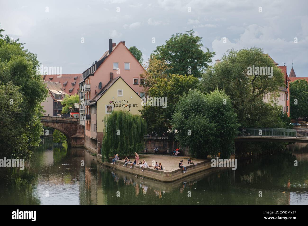 View of the love island with different people sitting outside on the river Pegnitz in the German city Nuremberg. Stock Photo