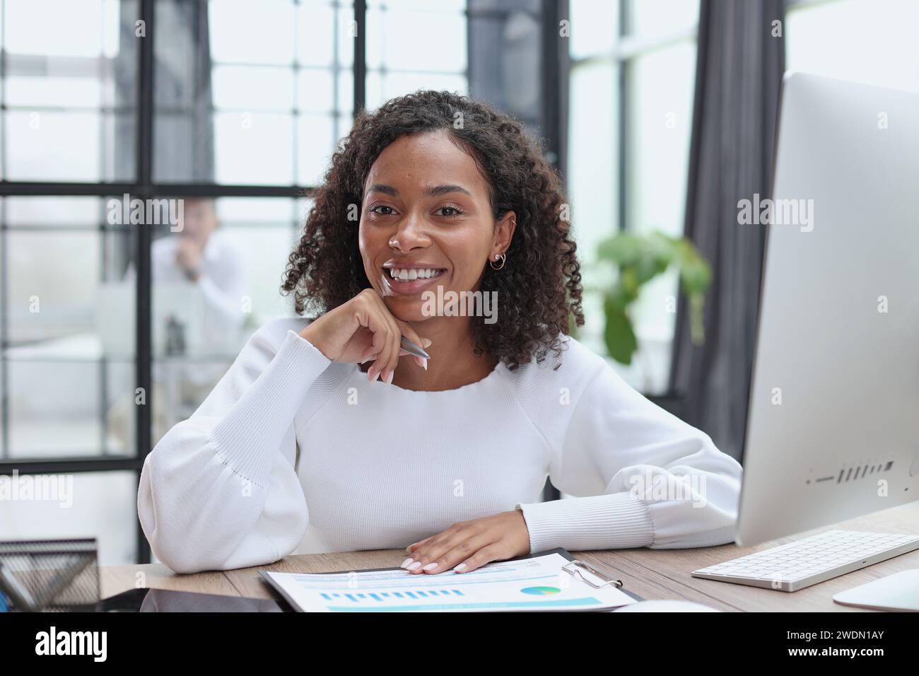 Waist up portrait of cheerful young mixed race female with curly Stock Photo