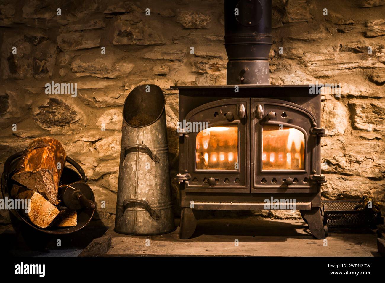 Traditional wood burner or wood burning stove in an old stone fireplace, UK Stock Photo