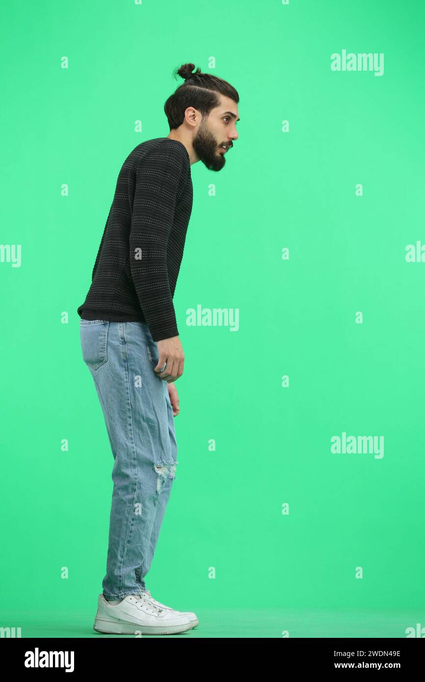 Distant Man A man, full-length, on a green background, looks into the distance ...