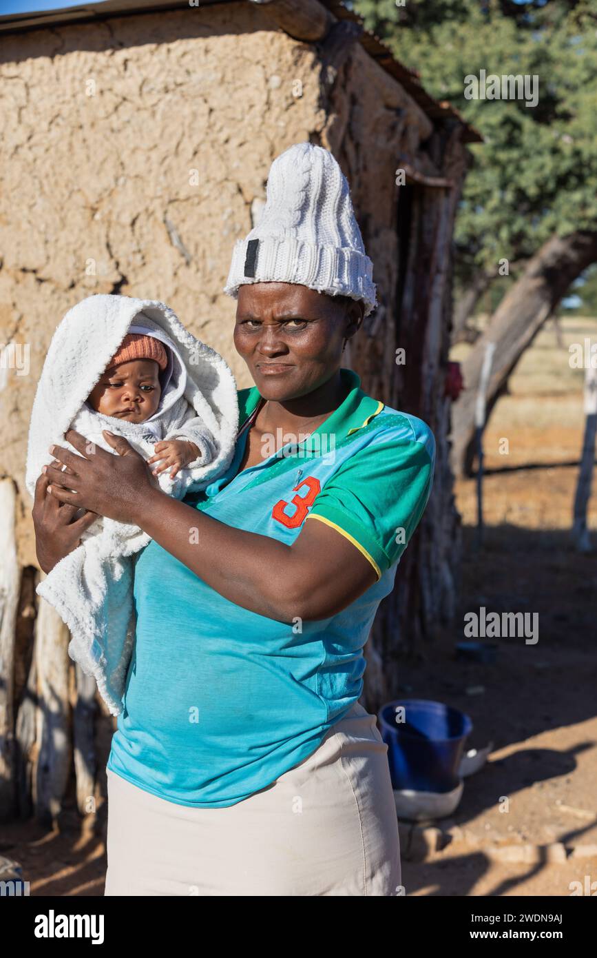 village african mother holding her child in front of the mud hut Stock Photo