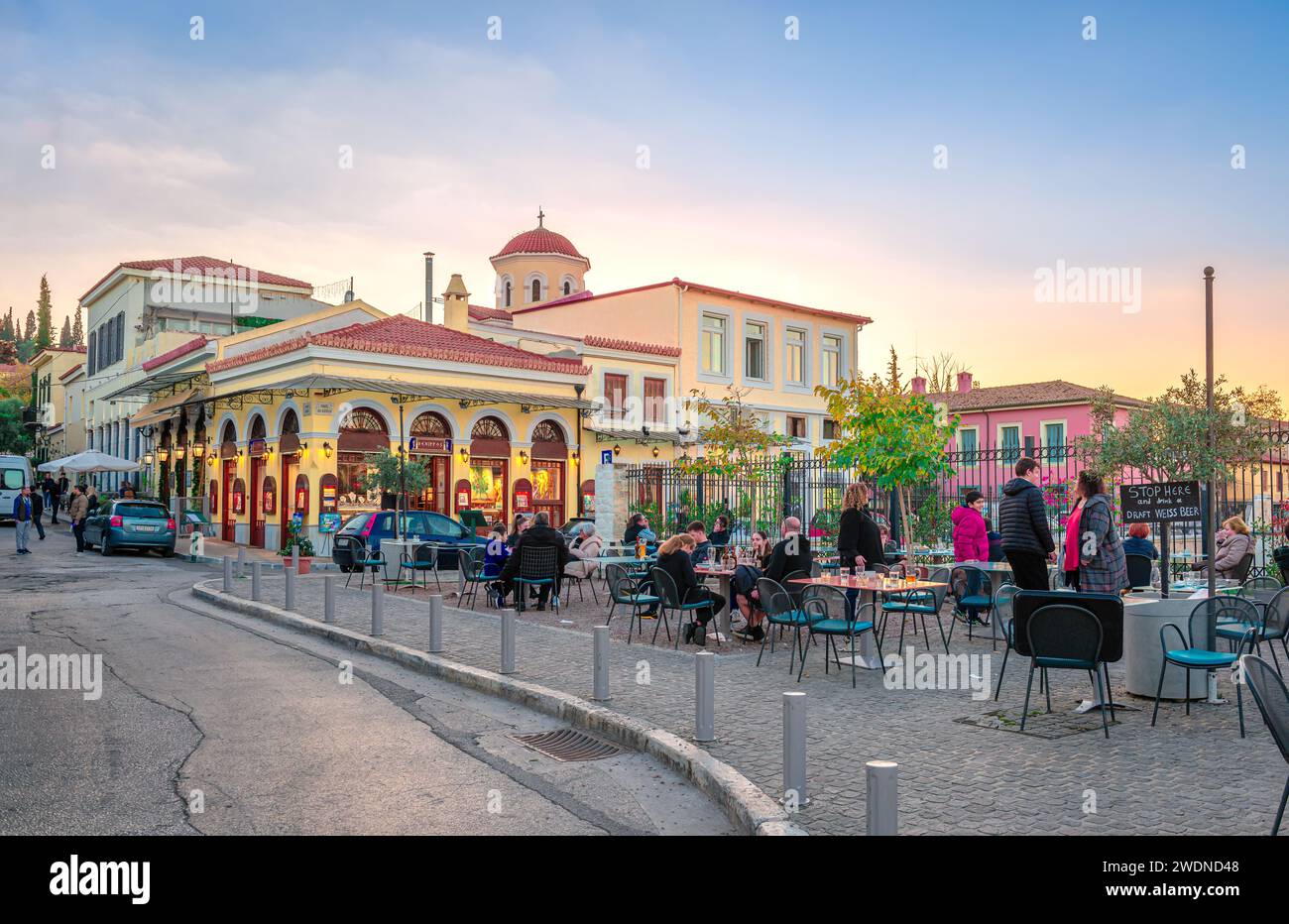 People in sidewalk café in Plaka, next to the Roman Agora, with old and neoclassical buildings. Athens, Greece. Stock Photo