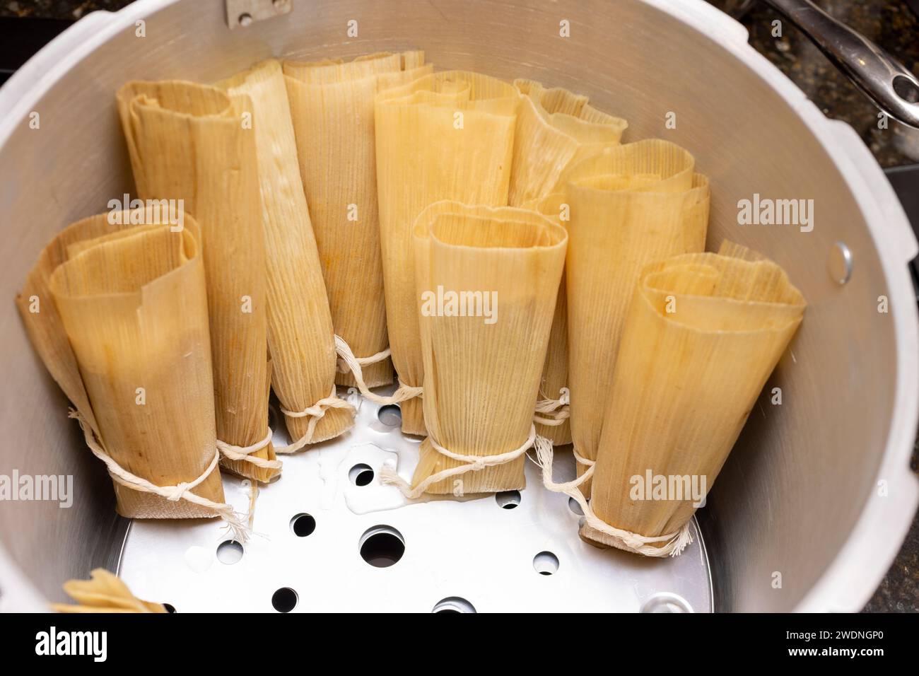 Red chili beef tamales being placed in a pot for the steaming process