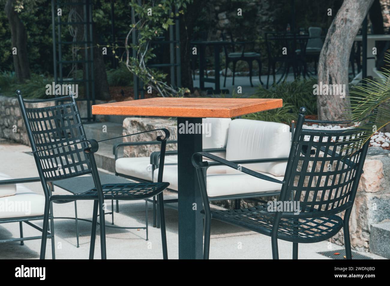 Cozy modern bistro outside in old town. Elegant restaurant in Europe. Urban cafe with chairs and high table. Idyllic ambiance in summer. Empty patio. Stock Photo