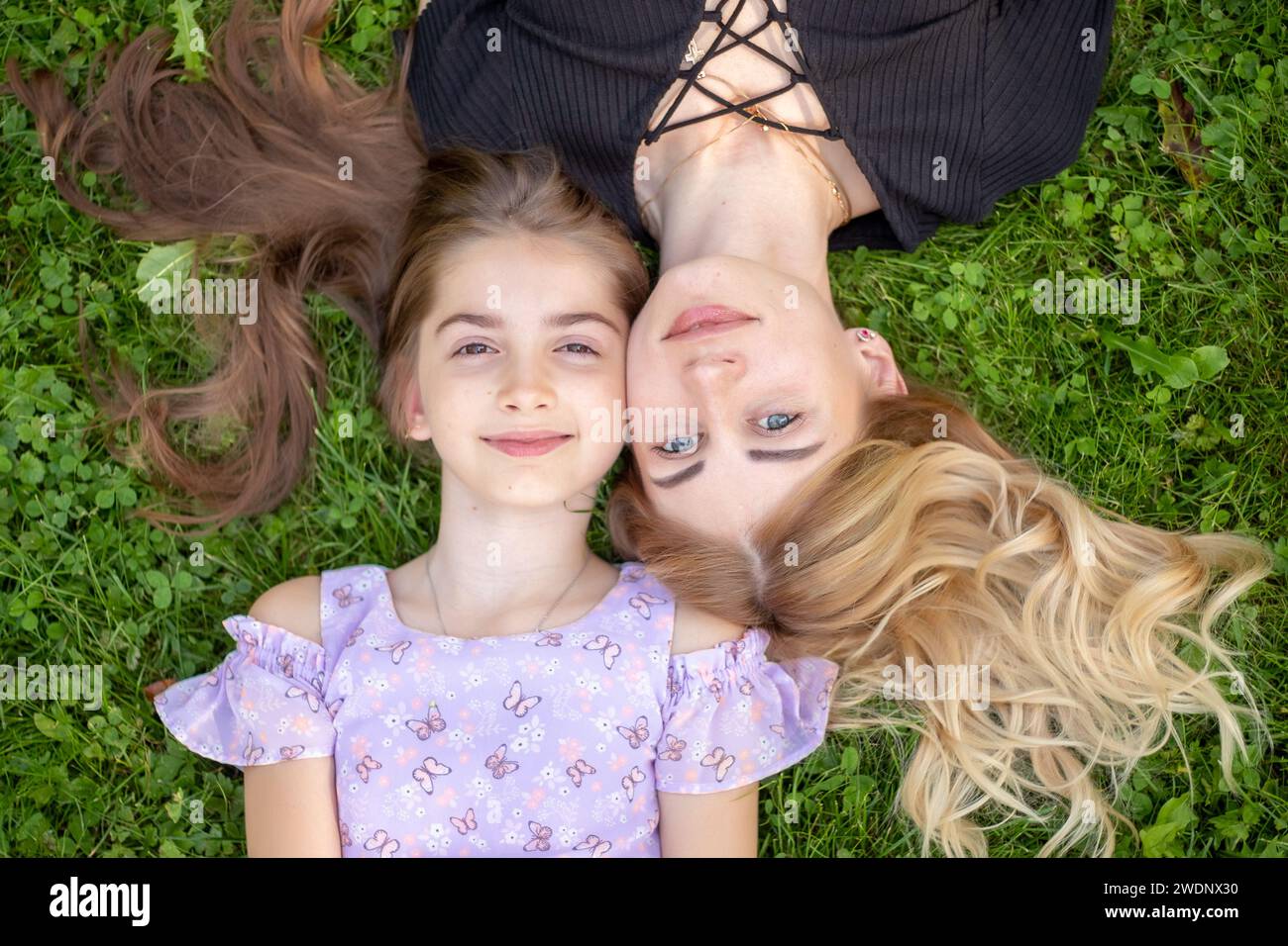 Mother and daughter lying on green grass. Stock Photo