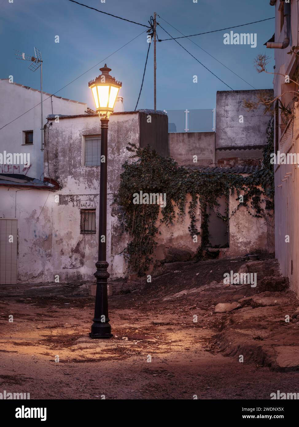 A remote derelict backstreet lit only by a single streetlight in San Miguel de Salinas, Alicante, Spain. Stock Photo