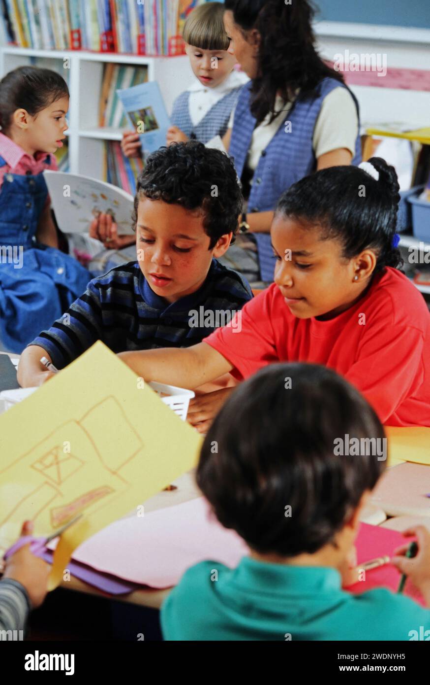 A Group Of Mixed Race Children Working Together At A Desk In The a-group-of-mixed-race-children-working-together-at-a-desk-in-the