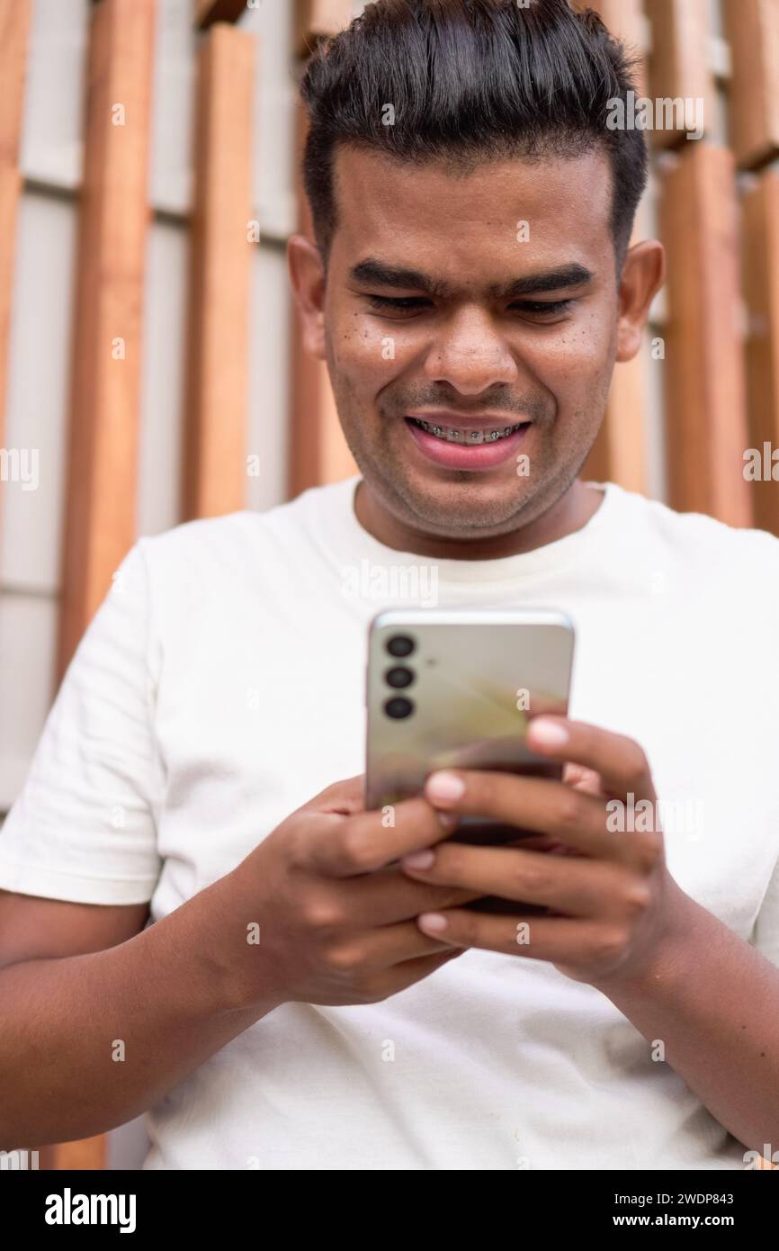 Latin Man with Braces Using Smartphone Stock Photo