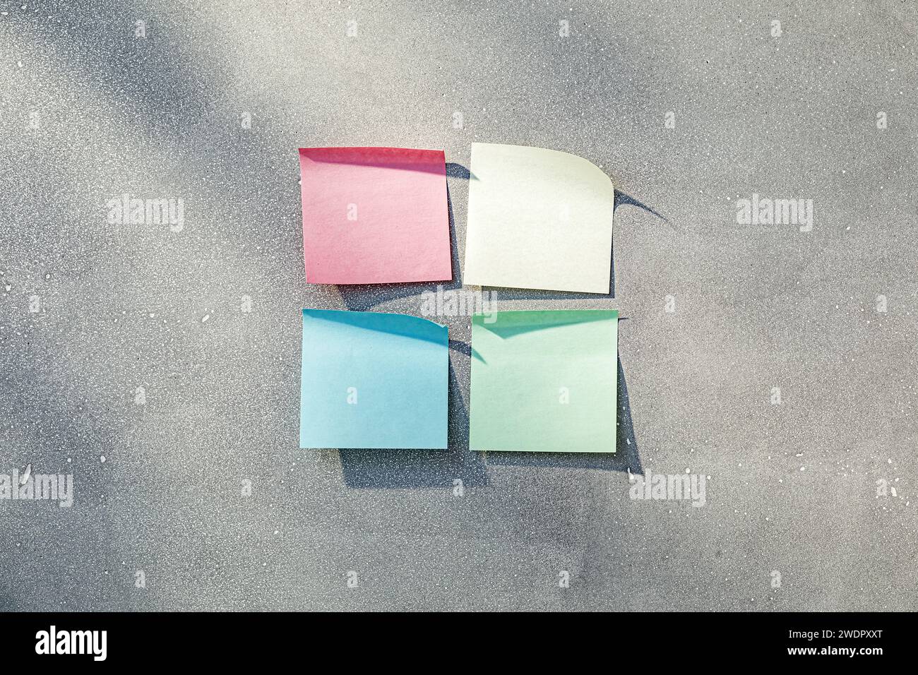 Four multicolored sticky notes in sunlight on gray concrete texture Stock Photo