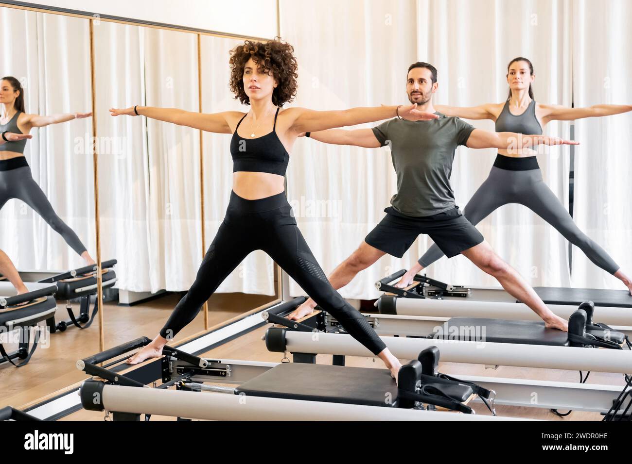 Pilates class of athletes doing a standing lunge exercise on
