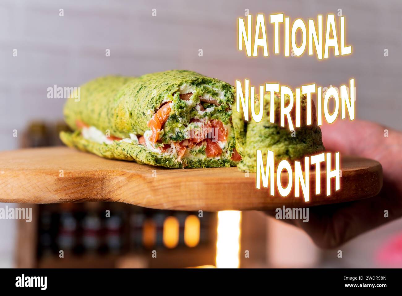 Green spinach wrap, stuffed with fresh ingredients, signifies the celebration of National Nutrition Month in the United States. Stock Photo