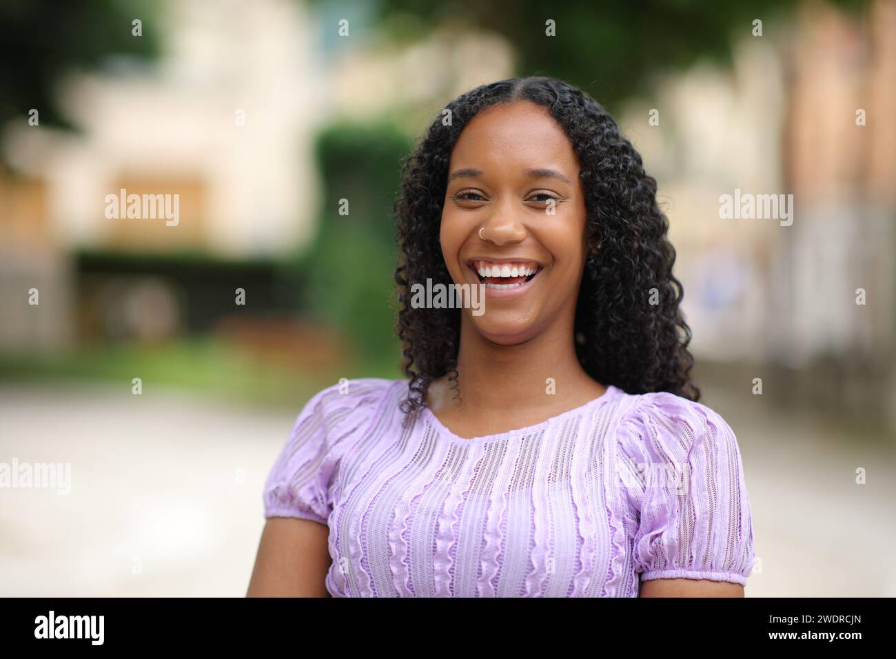 Front view portrait of a beautiful black woman with perfect teeth laughing at camera in the street Stock Photo