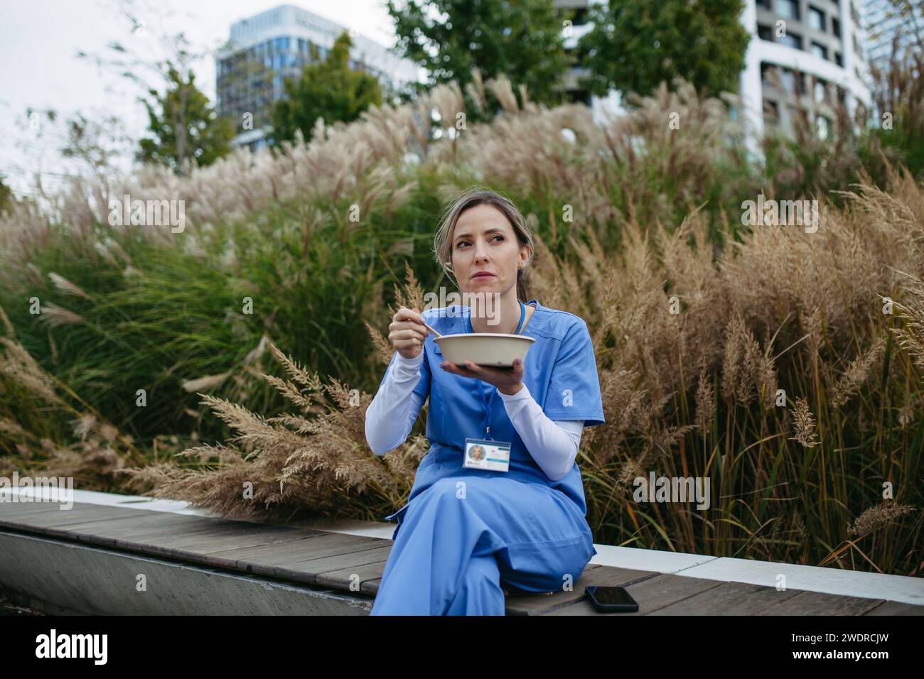 Nurse having healthy lunch, snack in front of hospital building, taking