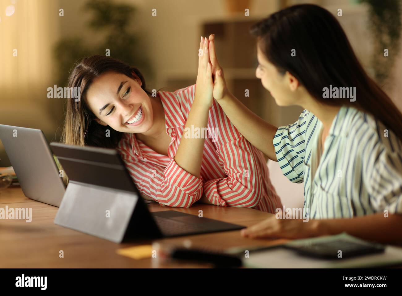 Happy tele workers celebrating giving five in the night at home Stock Photo