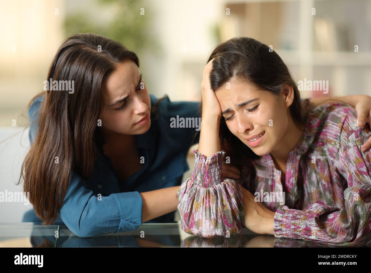 Good friend comforting a sad woman at home Stock Photo