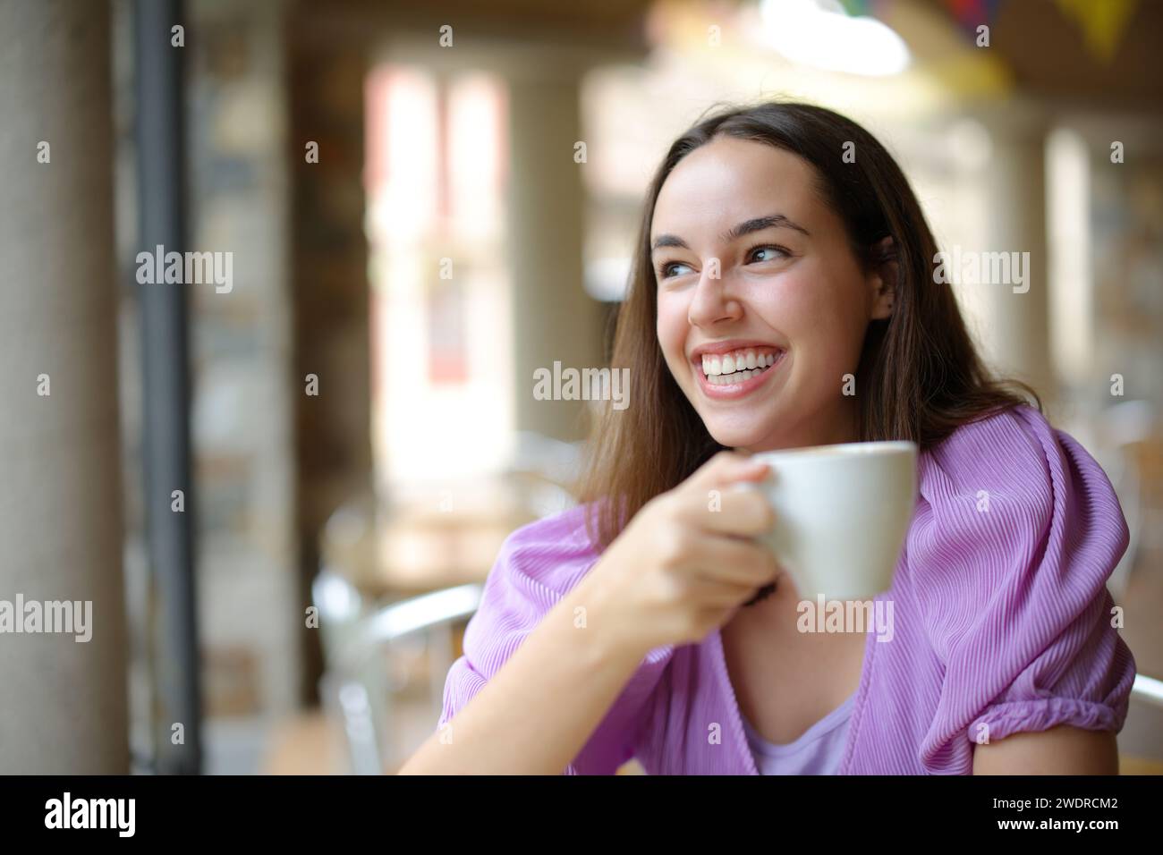 Happy woman drinking coffee and laughing looking away in a bar terrace Stock Photo