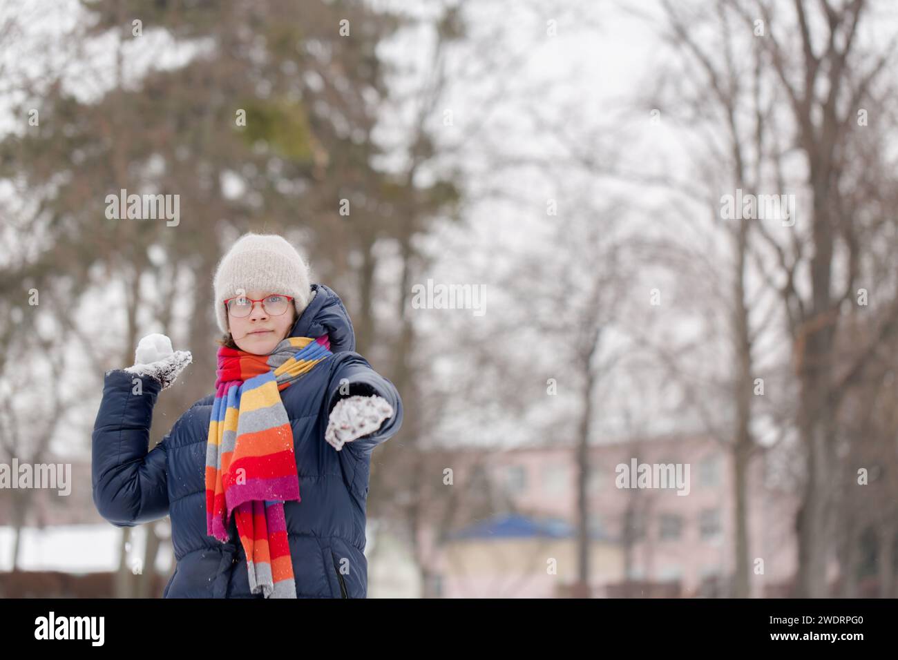 A teenage girl plays with snowballs in a winter park Stock Photo