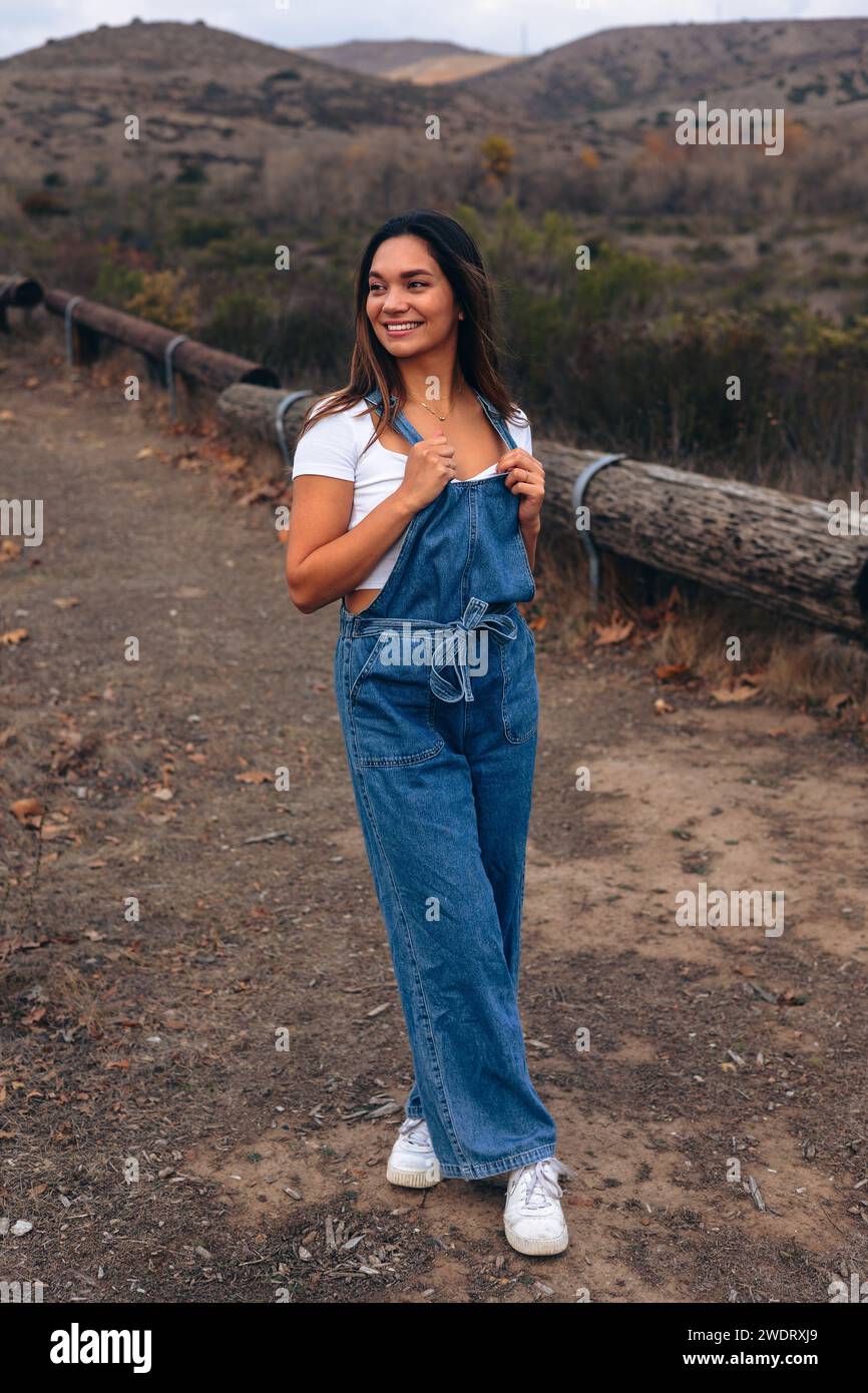 Young woman standing with legs crossed on hiking trail during fall Stock Photo