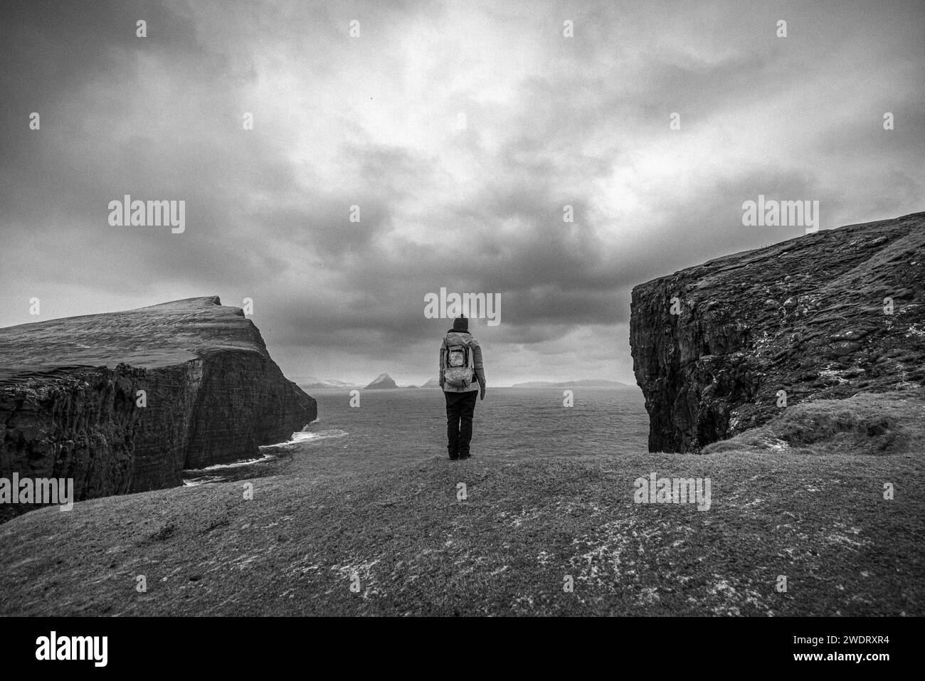 Black and white image of woman standing alone at edge of cliff. Stock Photo