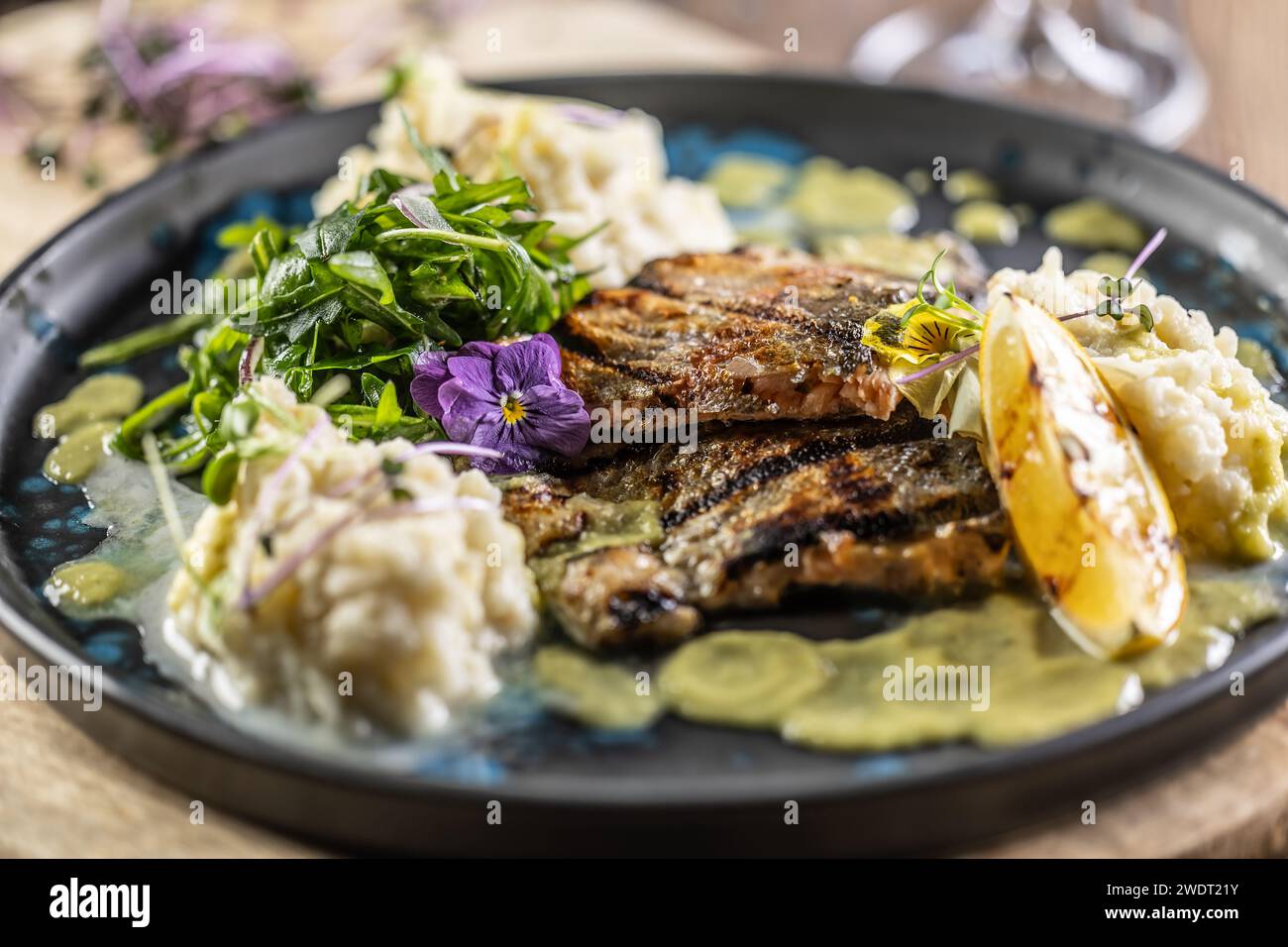 Grilled trout fillet with mashed potatoes and lemon sauce on a restaurant plate. Stock Photo