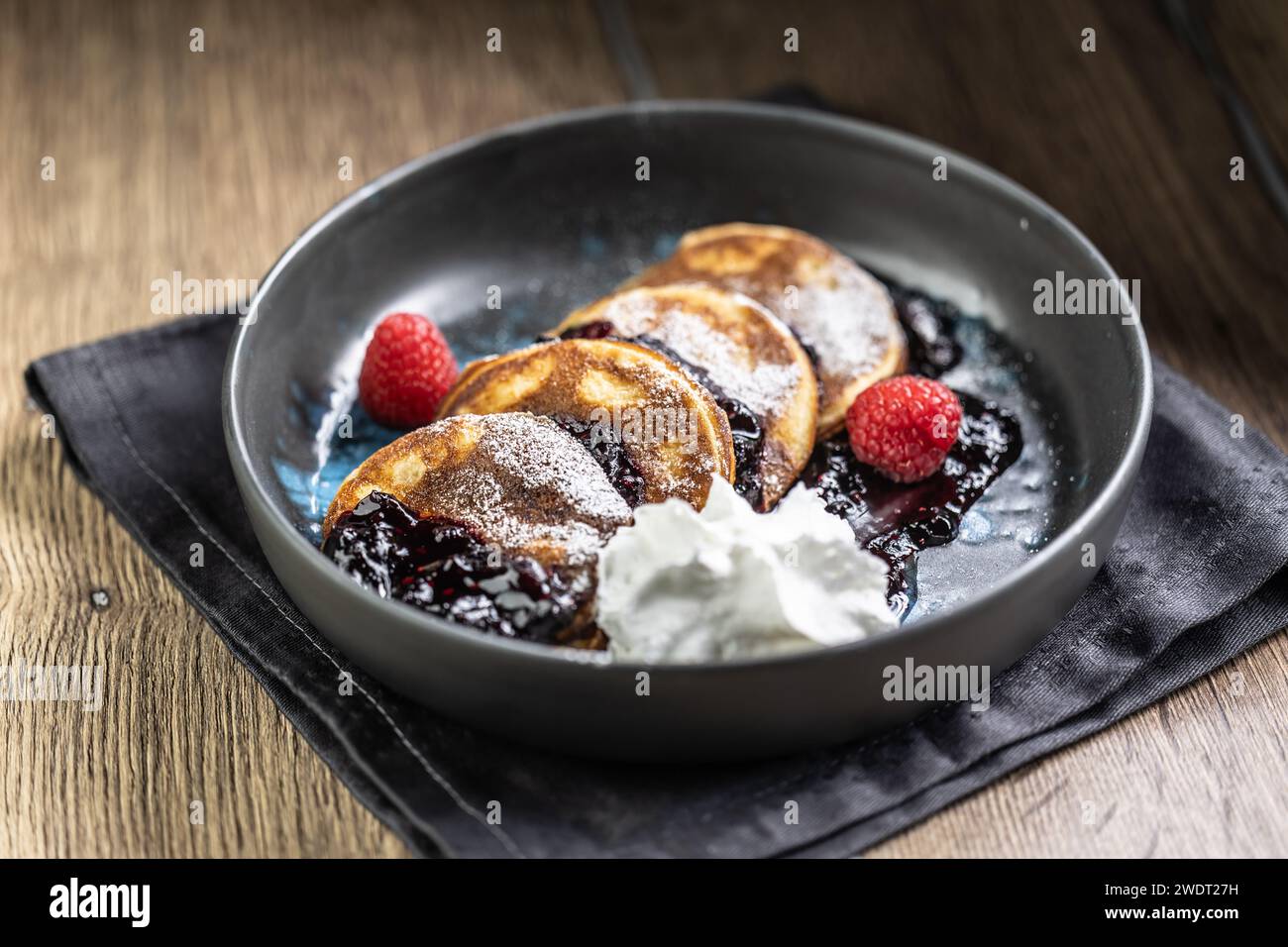 Pancakes with blueberry jam and raspberries in a bowl. Stock Photo