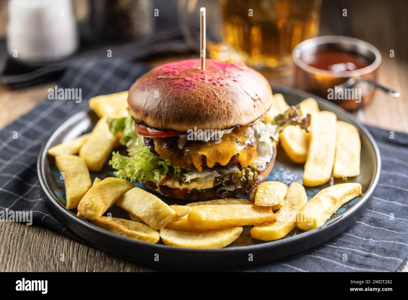 Beef burger with fries and draft beer on a pub or restaurant plate ...