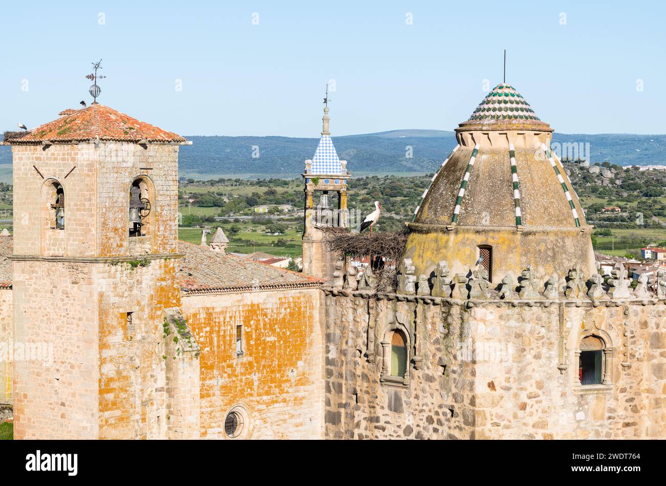 Nesting storks on the the Iglesia de San Martin, on the left and centre, and Torre del Alfiler, on the right, Trujillo, Caceres, Extremadura, Spain Stock Photo