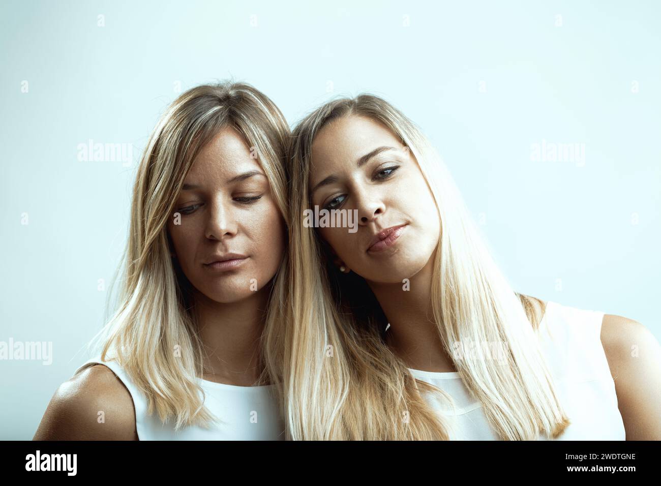 Melancholy embraces the women as they stand close, comfort found in their shared silence Stock Photo