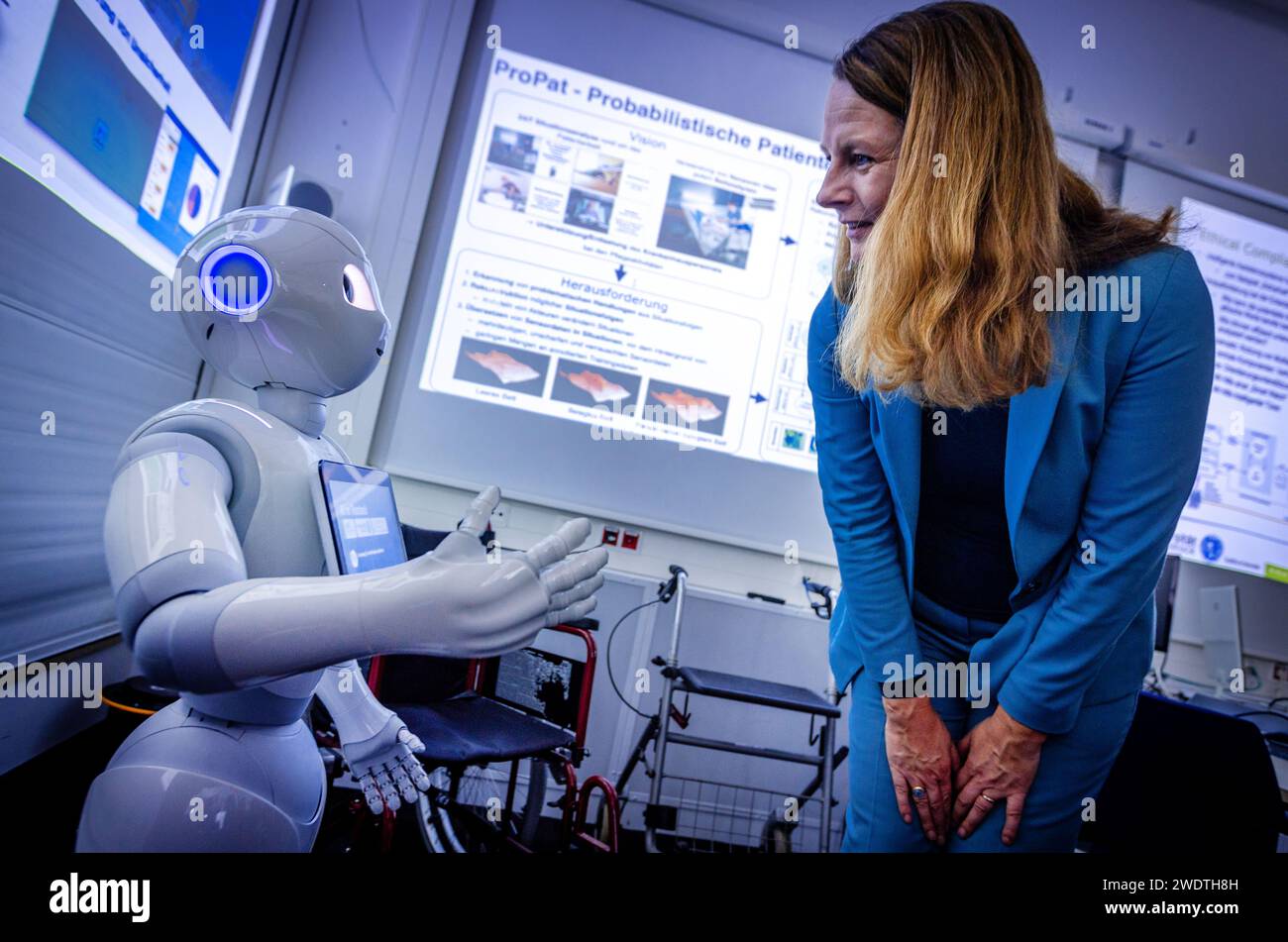 Rostock, Germany. 22nd Jan, 2024. Bettina Martin (SPD), the Minister of Science and European Affairs of Mecklenburg-Vorpommern, is greeted by the Pepper robot during a visit to the Center for Artificial Intelligence (AI) in Mecklenburg-Vorpommern at the University of Rostock. The robot, manufactured by the company Aldebaran Robotics, was programmed by the Rostock scientists for the care of stroke patients. During the visit, the work of the AI Center was presented and the 'Smart Appliance Laboratory' was toured. Credit: Jens Büttner/dpa/Alamy Live News Stock Photo