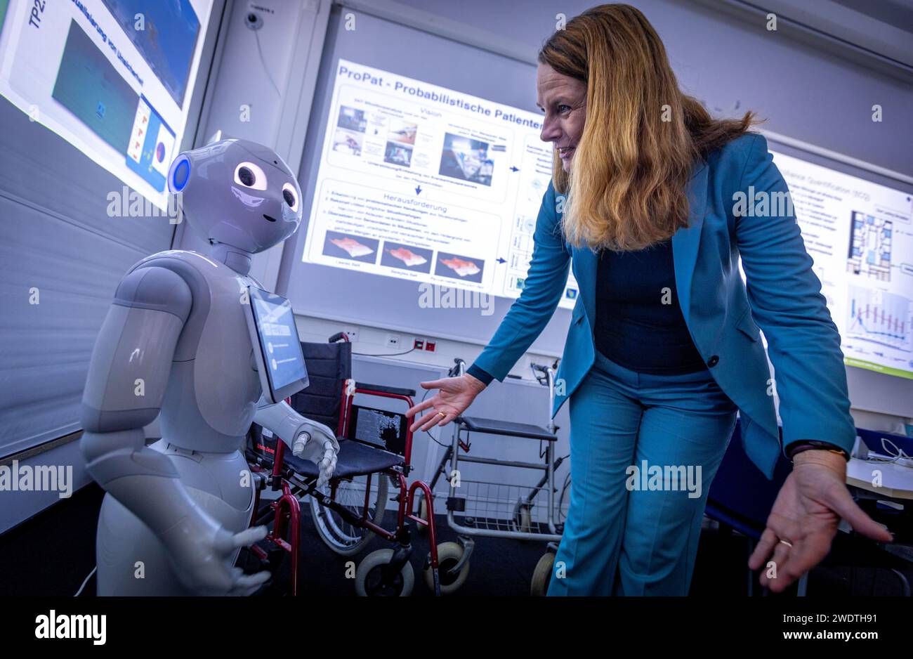 Rostock, Germany. 22nd Jan, 2024. Bettina Martin (SPD), the Minister of Science and European Affairs of Mecklenburg-Vorpommern, is greeted by the Pepper robot during a visit to the Center for Artificial Intelligence (AI) in Mecklenburg-Vorpommern at the University of Rostock. The robot, manufactured by the company Aldebaran Robotics, was programmed by the Rostock scientists for the care of stroke patients. During the visit, the work of the AI Center was presented and the 'Smart Appliance Laboratory' was toured. Credit: Jens Büttner/dpa/Alamy Live News Stock Photo