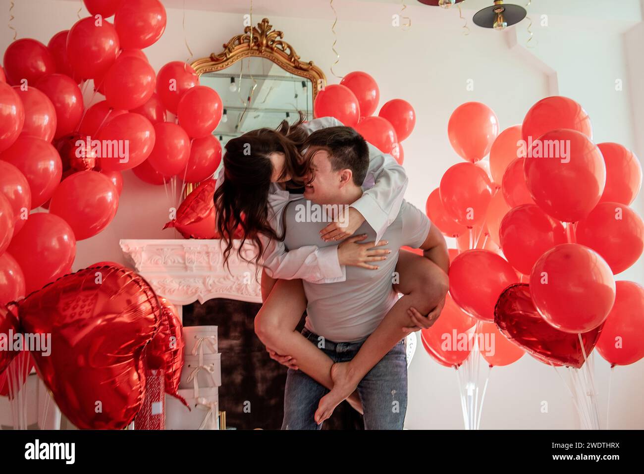 Playful, romantic moment between crazy couple near red balloons in 