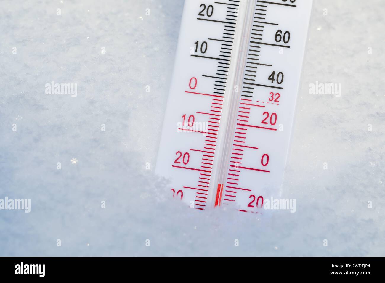 Thermometer with both Celsius and Fahrenheit scales placed in fresh snow indicating very cold winter temperature Stock Photo