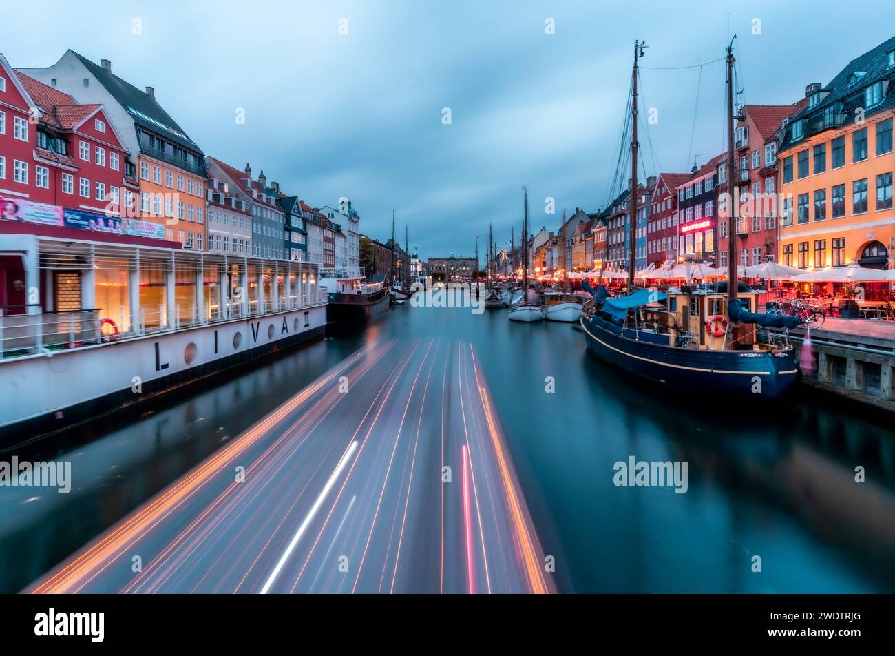 Twilight Symphony at Nyhavn: Long Exposure Captures Light Trails on Water Amidst the Iconic Colorful Buildings of Copenhagen Stock Photo
