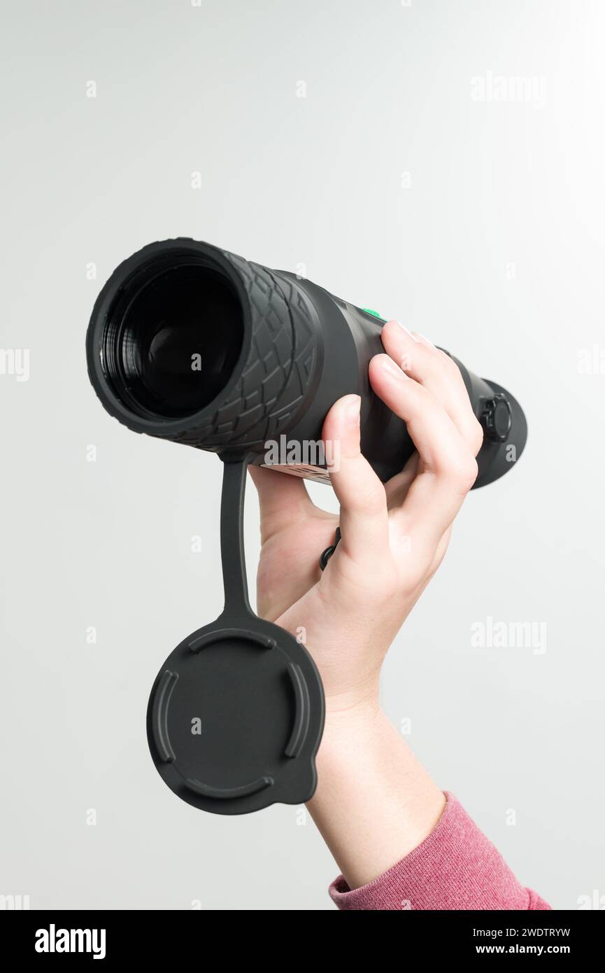 The child is holding a monocular on a white background, a long-range thermal imager. Stock Photo
