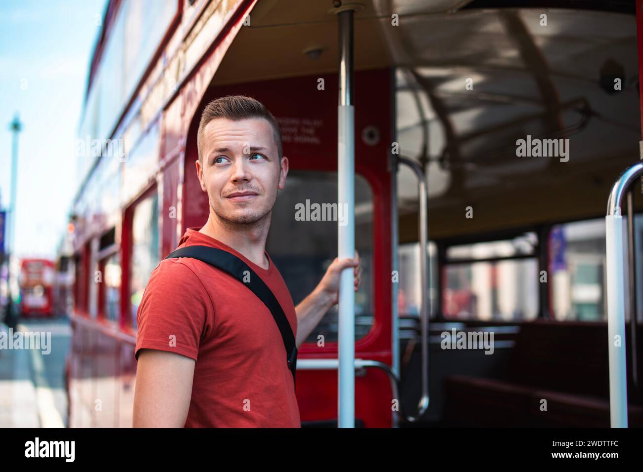 Portrait of tourist boarding to red double-decker bus in central London. United Kingdom. Stock Photo