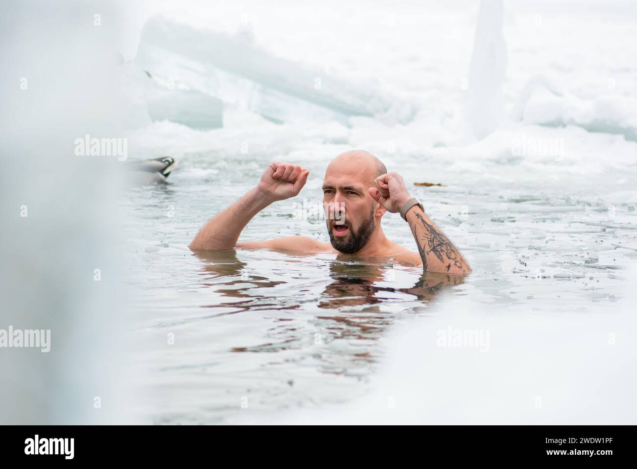 Handsome boy or man ice bathing in the freezing cold water of a frozen lake among ducks. Wim Hof Method, cold therapy, breathing techniques Stock Photo