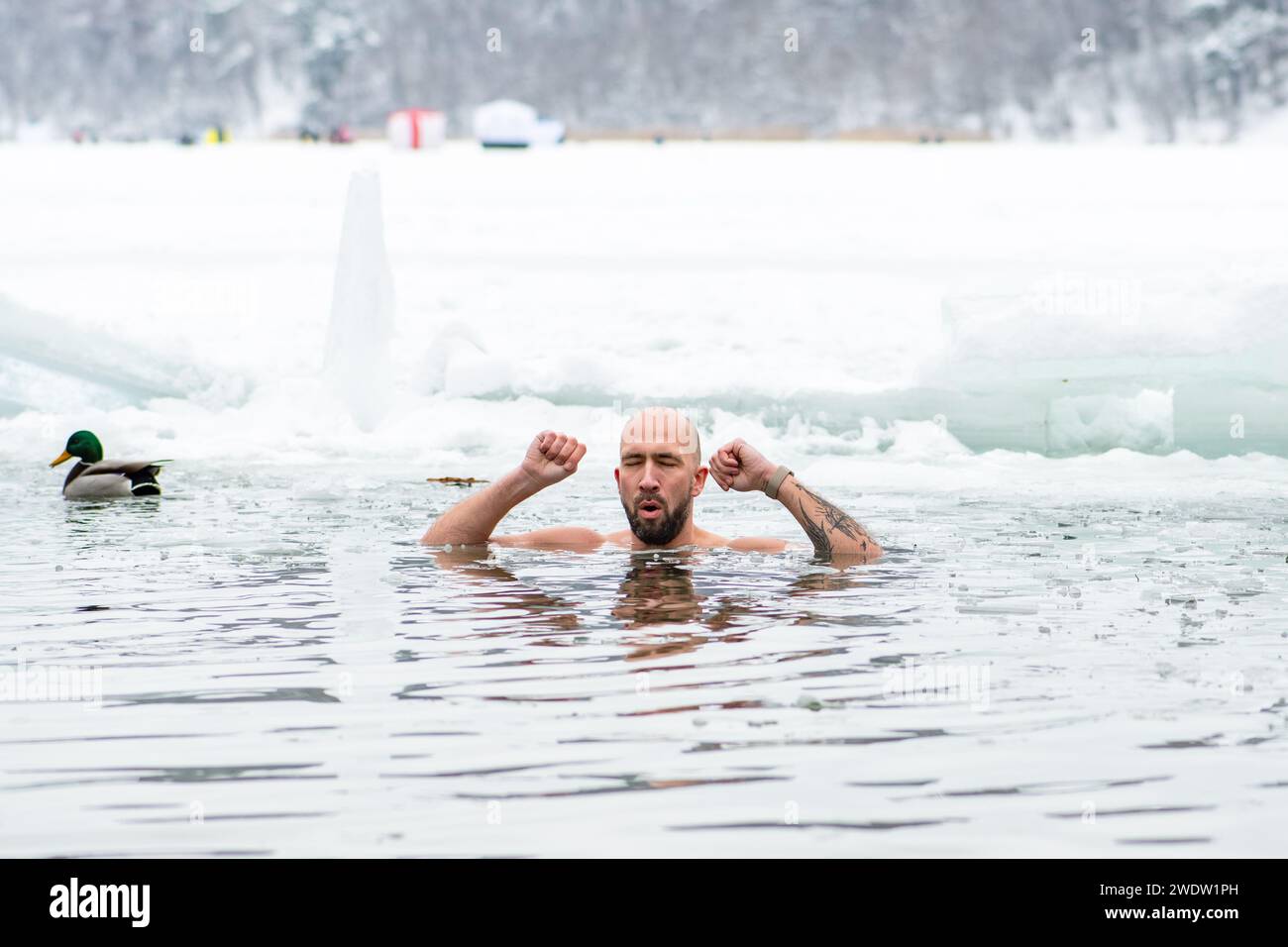 Handsome boy or man ice bathing in the freezing cold water of a frozen