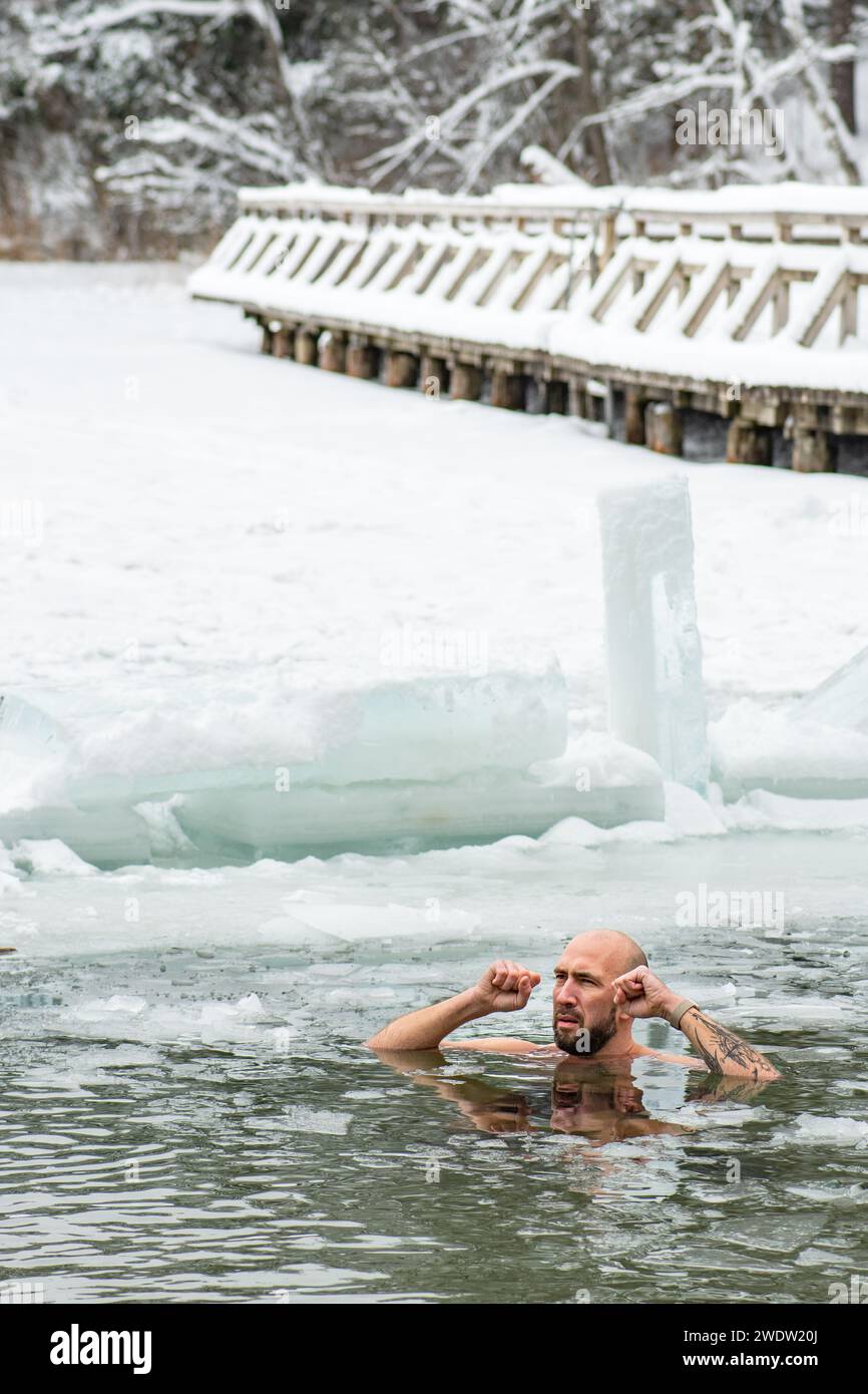 Handsome boy or man ice bathing in the freezing cold water of a frozen
