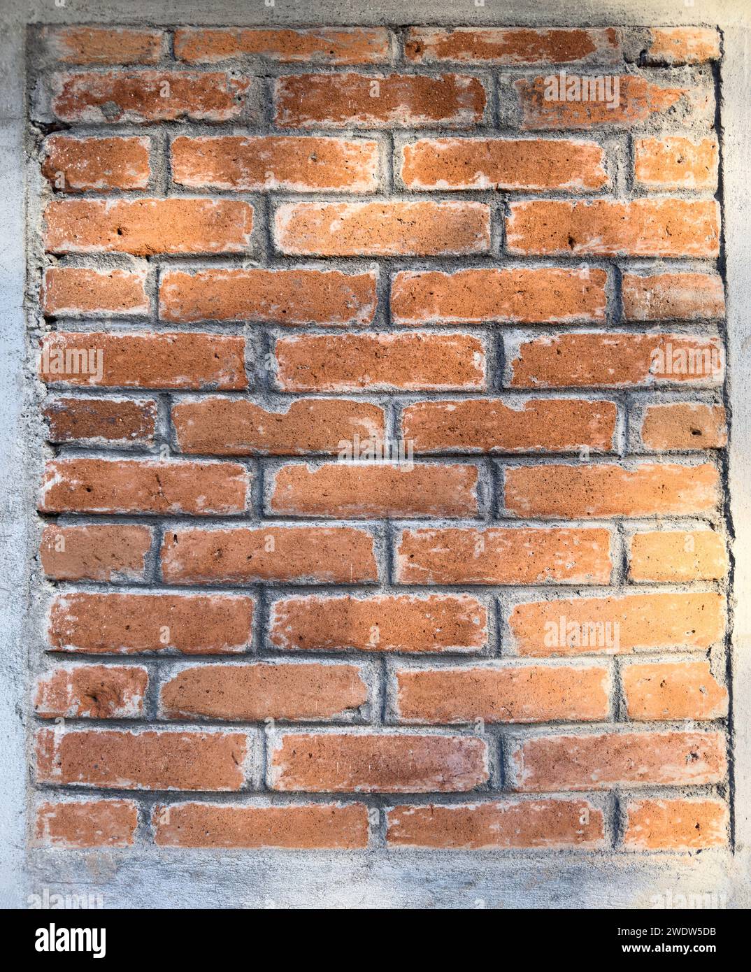Red aged brick wall with cement frame around in square wall Stock Photo